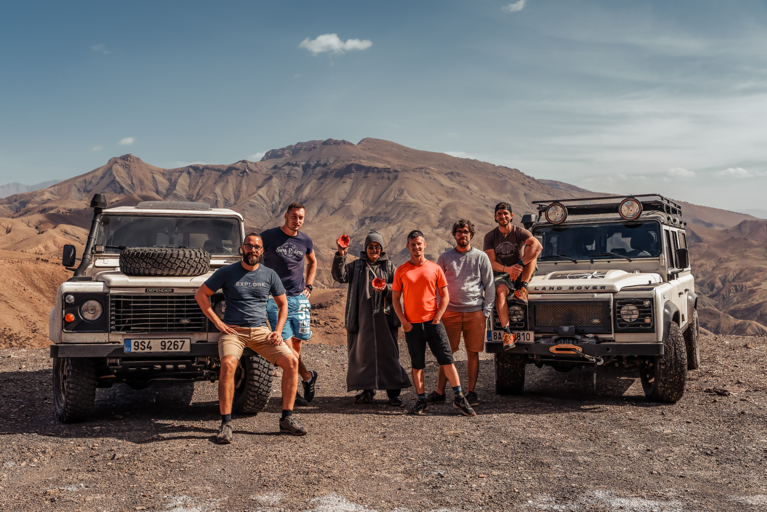 Skupina cestovatelů s vozy Land Rover Defender v horském průsmyku Tizi n'Tichka v Maroku.