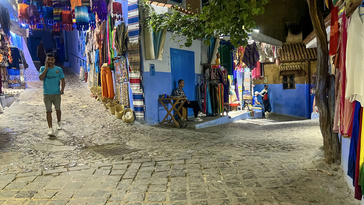 Večerní trh v modrých uličkách města Chefchaouen s barevnými koberci a lampióny