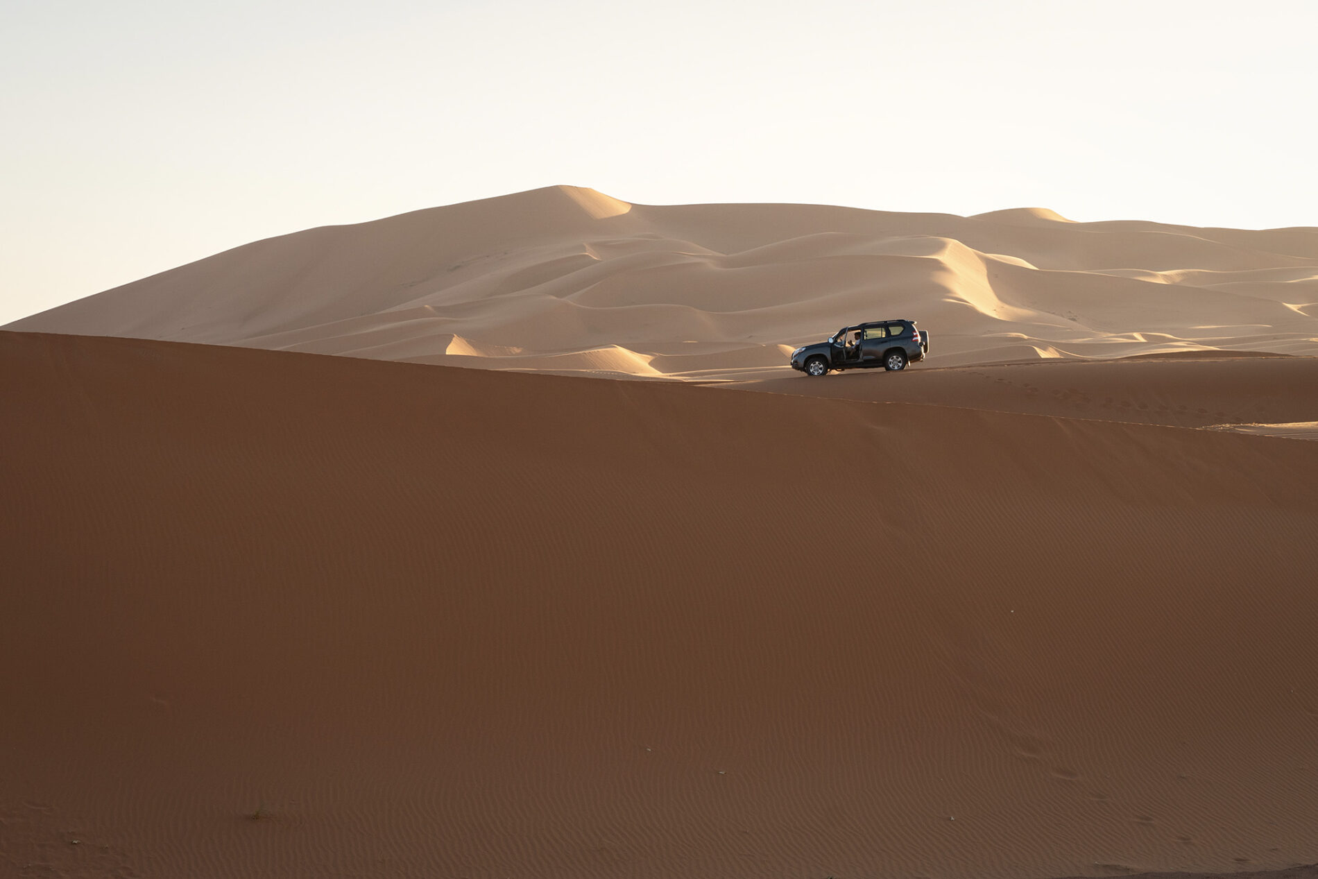 Terénní vůz Toyota Land Cruiser na vrcholu písečné duny Erg Chebbi v Merzouze v Maroku, expediční off-road jízda v poušti