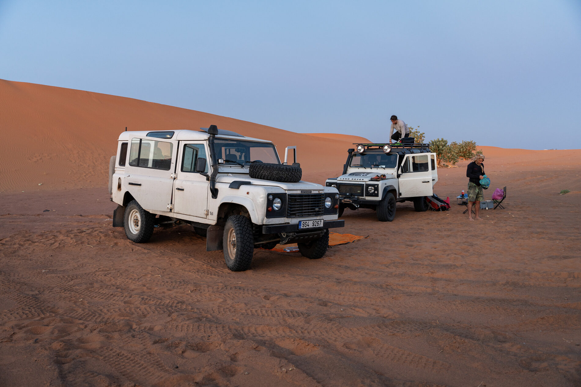 Příprava tábořiště expedičních vozů Land Rover Defender v písečných dunách Erg Chebbi u Merzougy v Maroku, cestování v poušti